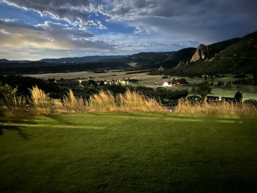 Scenic twilight view of a lush golf course and valley, highlighted by dramatic clouds.