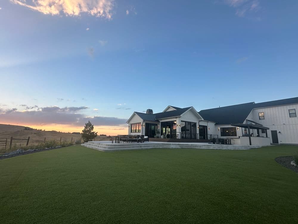 Contemporary house with manicured lawn and sunset view over rolling hills.