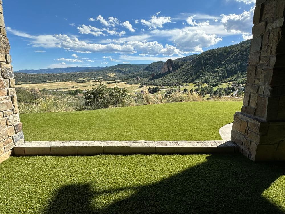 Scenic mountain view from a stone patio overlooking lush green landscape.
