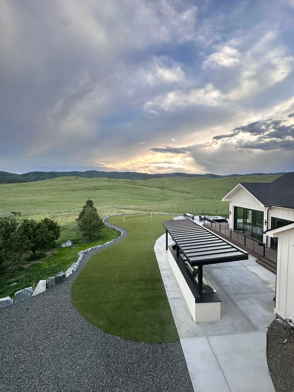 Scenic view of a lawn and patio at sunset, with mountains in the background.