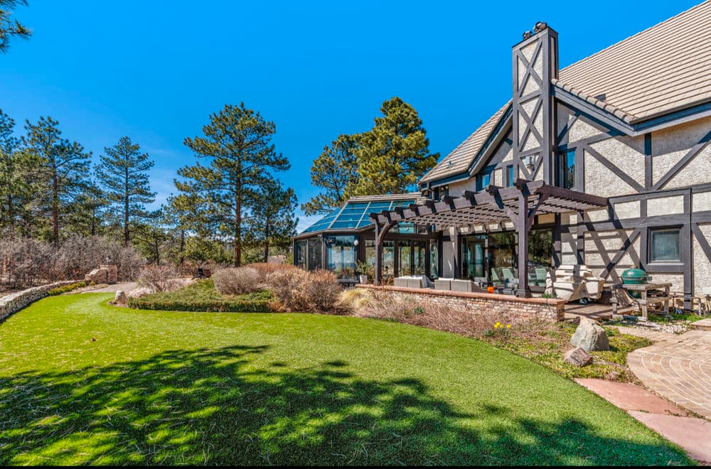 Beautiful modern home with garden, patio, and solar panels surrounded by trees.